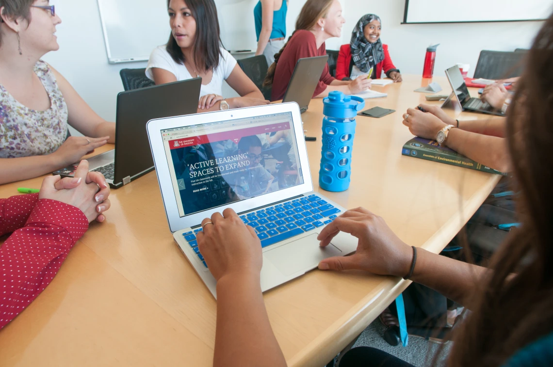 Students gathered around their laptops, talking